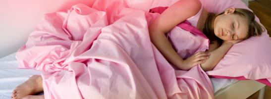 Bild på en ung kvinna som ligger i sin säng. Bilden illustrerar att du kan använda tampong under natten och slippa oroa dig för mens.