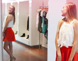 Ung kvinna står framför en spegel och provar nya kläder. Bilden illsutrerar hur en ung kvinnas kropp förändras under puberteten.